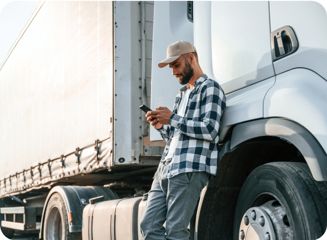 A driver leaning against a large white truck and using the Tachogram app on mobile phone.